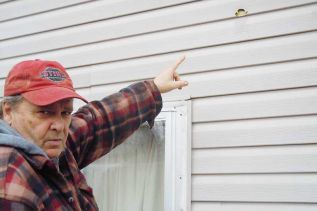 Arden resident Bob Woodcock points to the damage done to his Arden home by an apparent drive-by paint gun shooting on Halloween